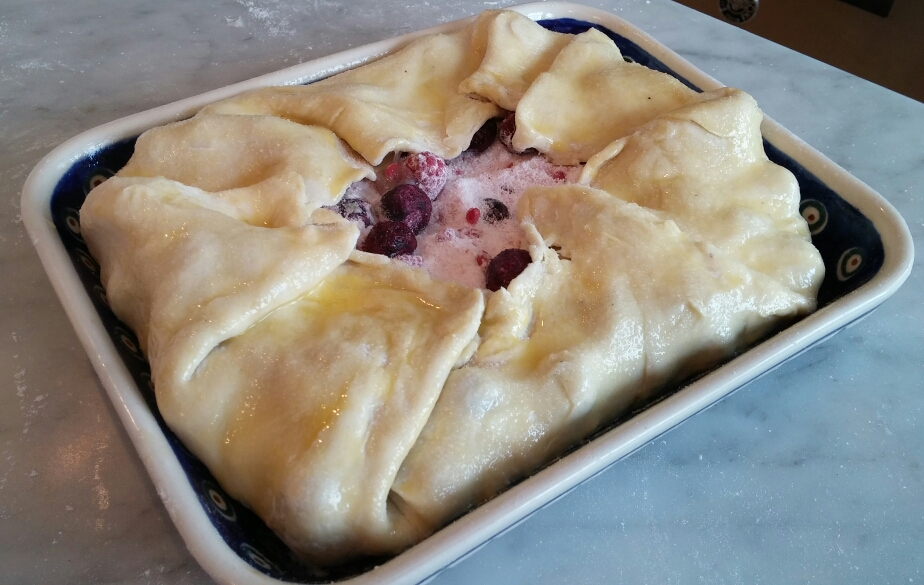 Fold the dough up and over the frozen berries, paint with egg wash, and sprinkle with granulated sugar