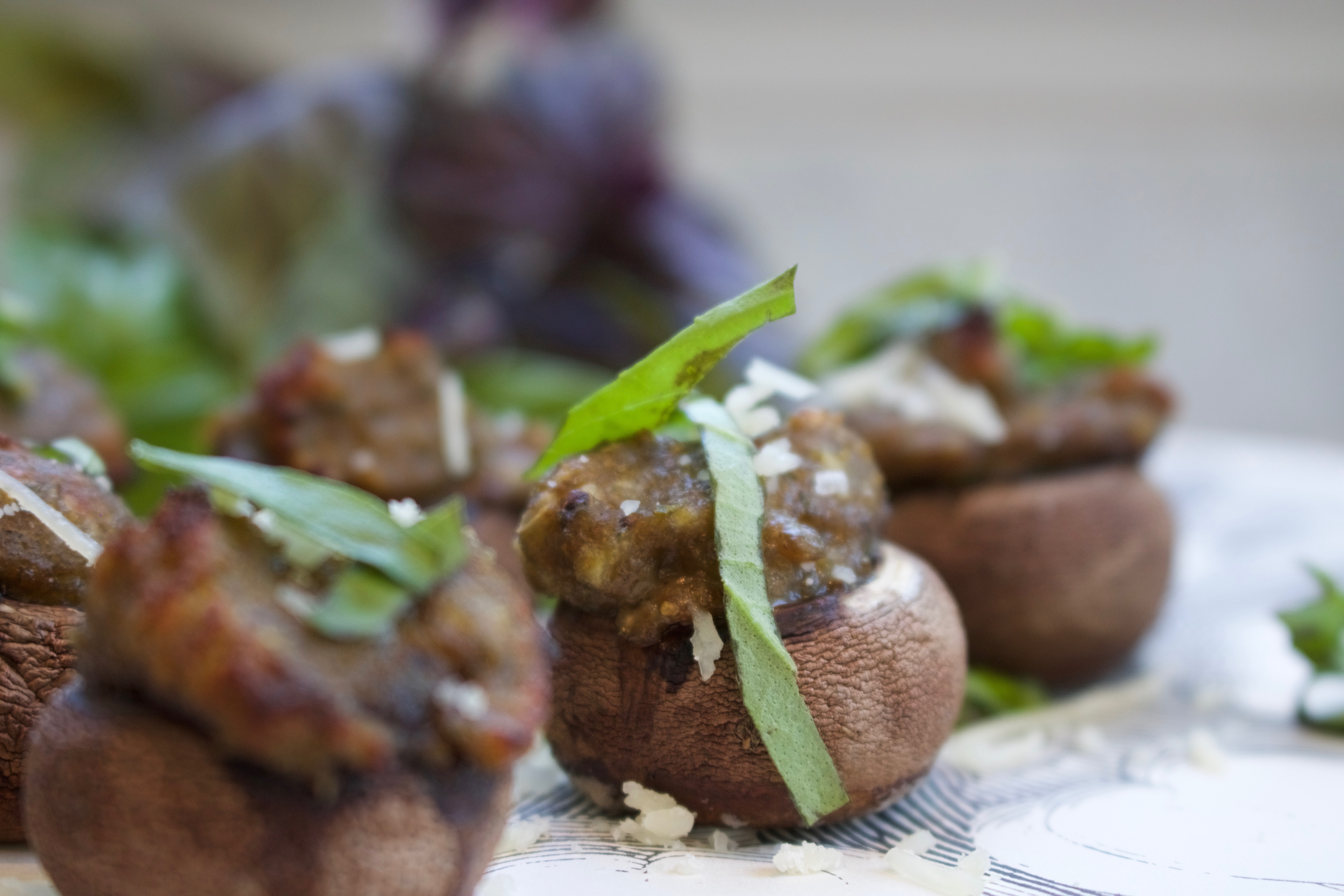 Basil, Parmesan Cheese and breadcrumbs stuffed mushroom caps garnished with p. cheese and basil strips